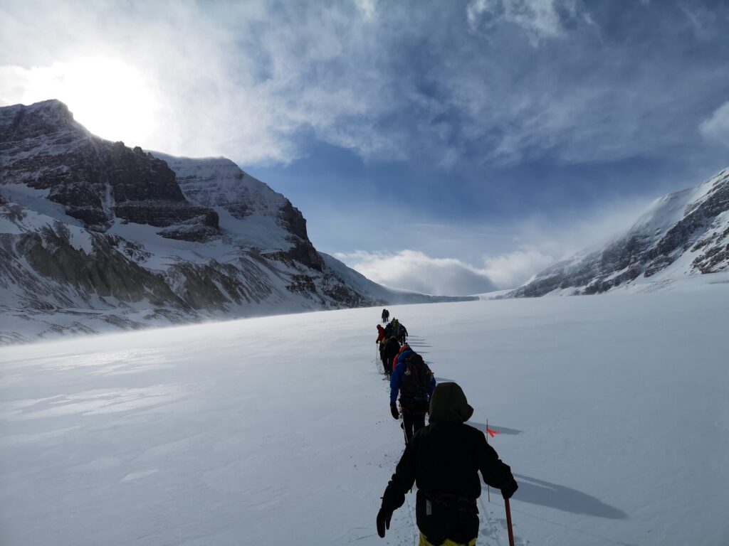 Two hikers crossing a snowfield toward mountain peaks