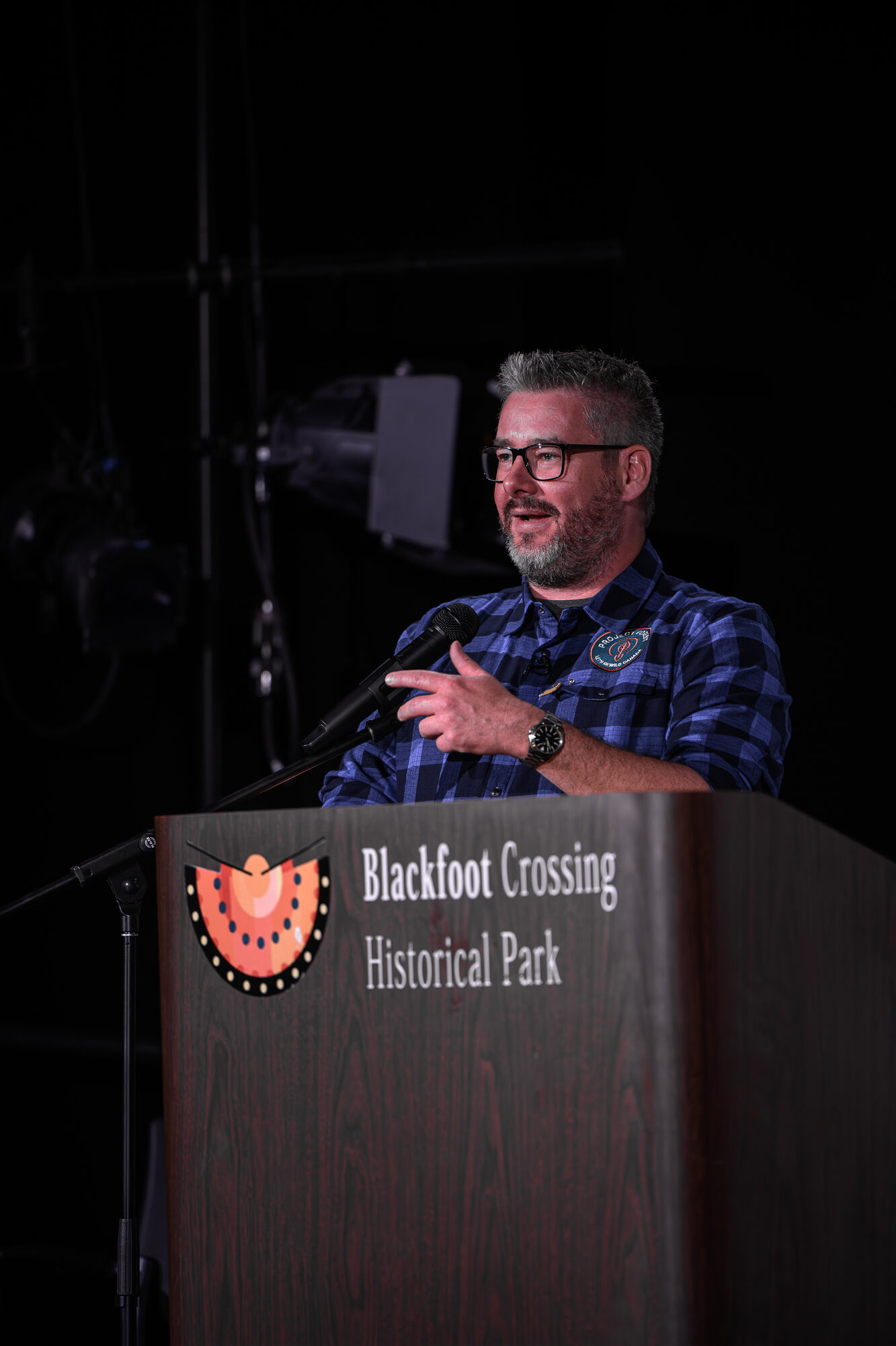 Mike Toffan speaking at a podium at Blackfoot Crossing Historical Park