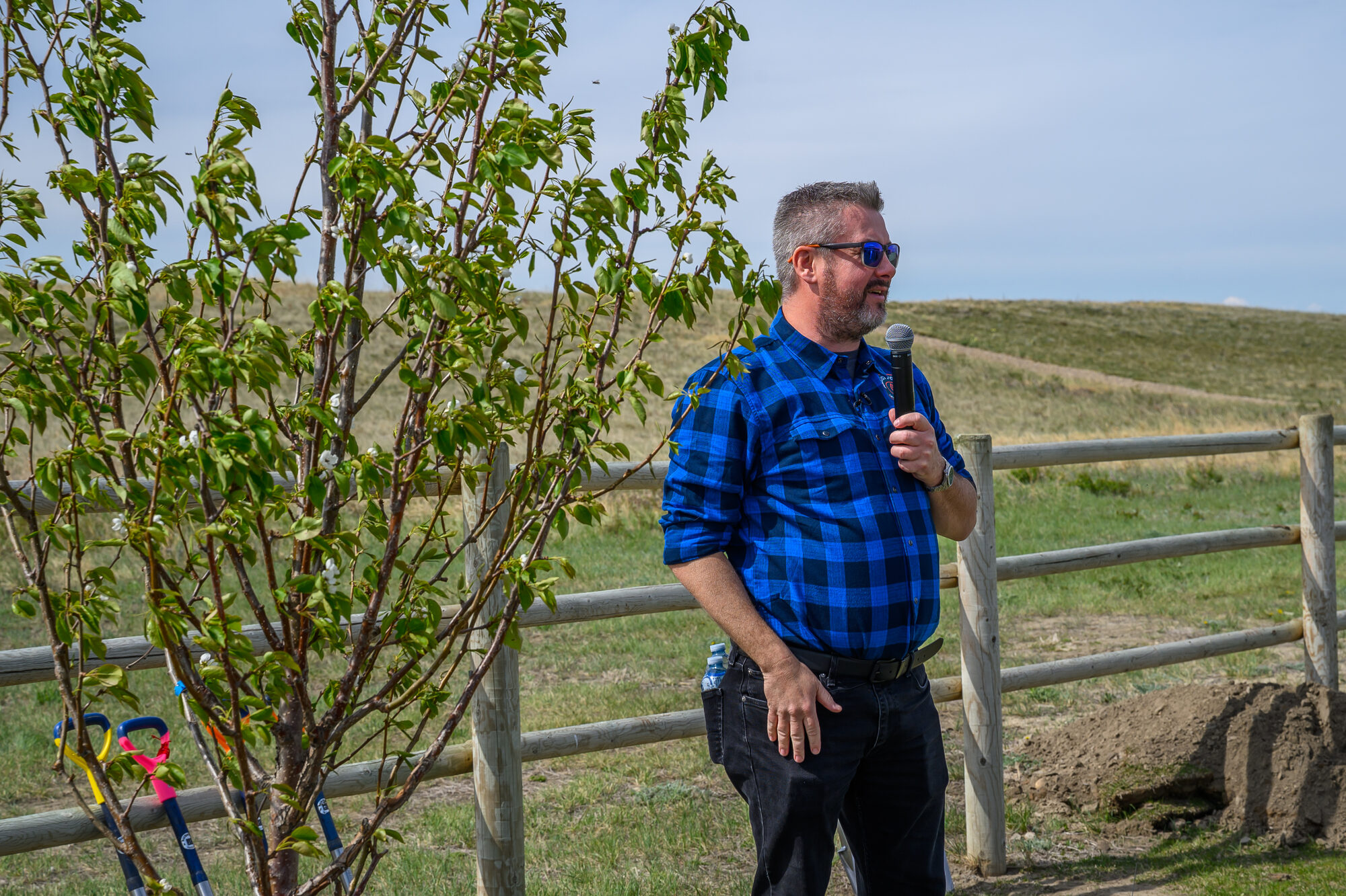 Mike Toffan speaking into a microphone at an outdoor event